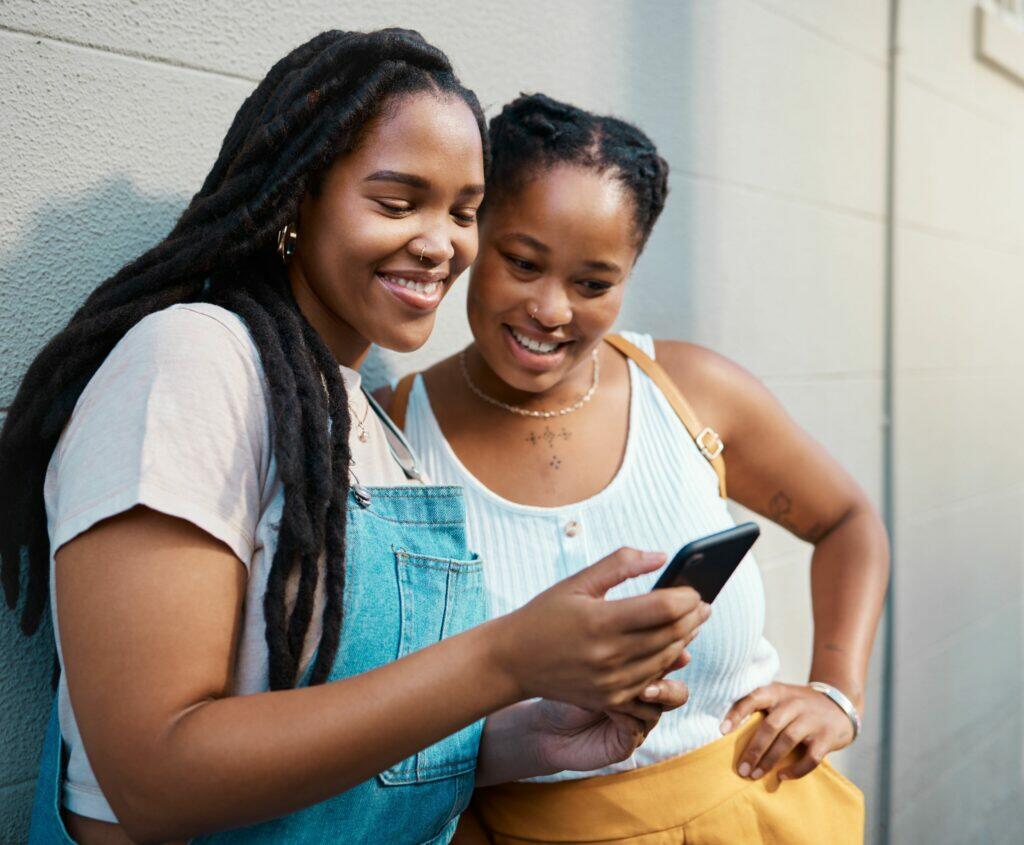 Two smiling youth looking at a phone