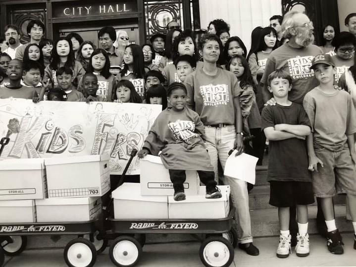 A black and white image of group of people wearing Kids First t-shirts at City Hall